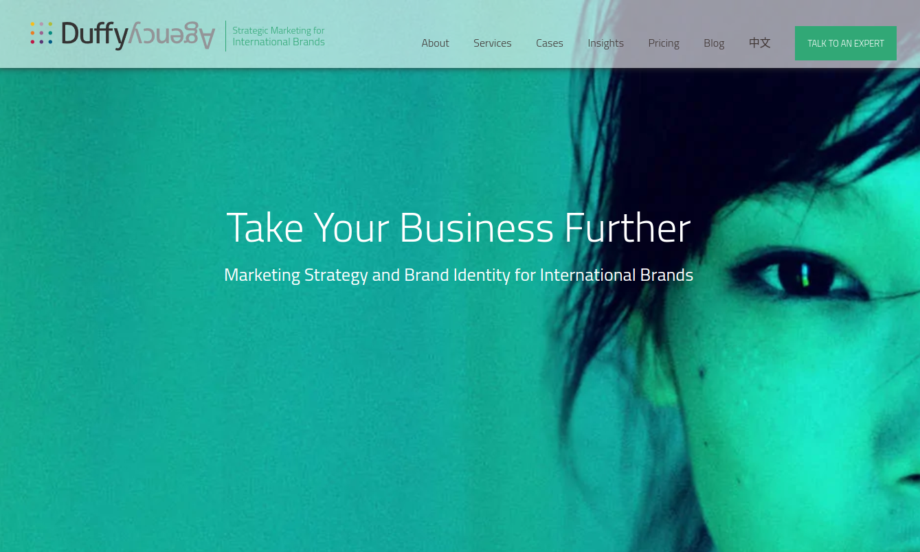 ```json
{
  "alt": "Duffy Agency website with branding message and partial face image.",
  "caption": "Elevate your brand with Duffy Agency's strategic marketing expertise. Connect globally with impactful identity solutions.",
  "description": "The Duffy Agency website features a teal background with a partial view of a woman's face. The tagline 'Take Your Business Further' promotes marketing strategy and brand identity for international brands. The navigation bar includes options like About, Services, Cases, Insights, Pricing, Blog, and a CTA 'Talk to an Expert.' The modern design and engaging visuals aim to attract businesses looking to expand their global reach."
}
```