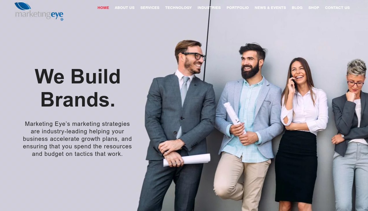 ```json
{
  "alt": "Four professionals stand together smiling, representing teamwork and branding.",
  "caption": "Four colleagues share a light moment, embodying the spirit of teamwork and innovation essential for brand building.",
  "description": "The image shows four professionally dressed individuals standing against a light gray backdrop, engaging in a cheerful moment. This represents a collaborative and positive work environment focused on brand building, as emphasized by the text beside them: 'We Build Brands.' Keywords: teamwork, branding, business strategy, professional."
}
```