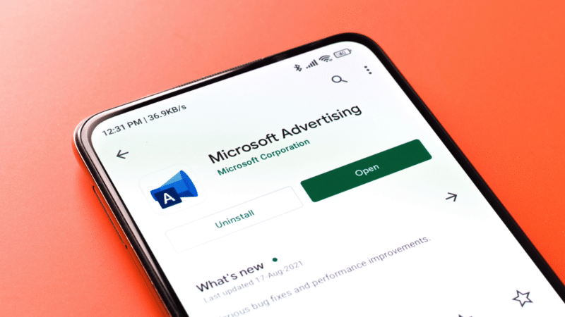 ```json
{
"alt": "Smartphone screen showing Microsoft Advertising app on Google Play Store over orange background.",
"caption": "Exploring advertising potential? Check out Microsoft Advertising on the Play Store, your gateway to enhanced marketing strategies and tools.",
"description": "This image displays a smartphone screen with the Microsoft Advertising app open on the Google Play Store. The app's page is shown, featuring options like 'Uninstall' and 'Open,' against a vibrant orange background. The display indicates the app's importance in digital marketing, offering tools and updates to optimize ad strategies. This visual emphasizes mobile accessibility and the significance of tech-driven advertising solutions. Keywords include Microsoft Advertising, Play Store, marketing, and app."
}
```