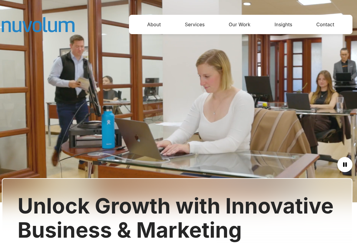 ```json
{
  "alt": "Office environment with people working at desks, featuring a prominent nuvolum logo.",
  "caption": "Dive into the dynamic office life at Nuvolum, where innovation in business and marketing takes center stage.",
  "description": "This image showcases a modern office environment with several people working at desks. The foreground features a woman focused on her laptop, while others work in the background. The nuvolum logo is prominently displayed, indicating the company's presence in innovative business and marketing solutions. Natural lighting and wooden office decor enhance the professional yet inviting atmosphere."
}
```
