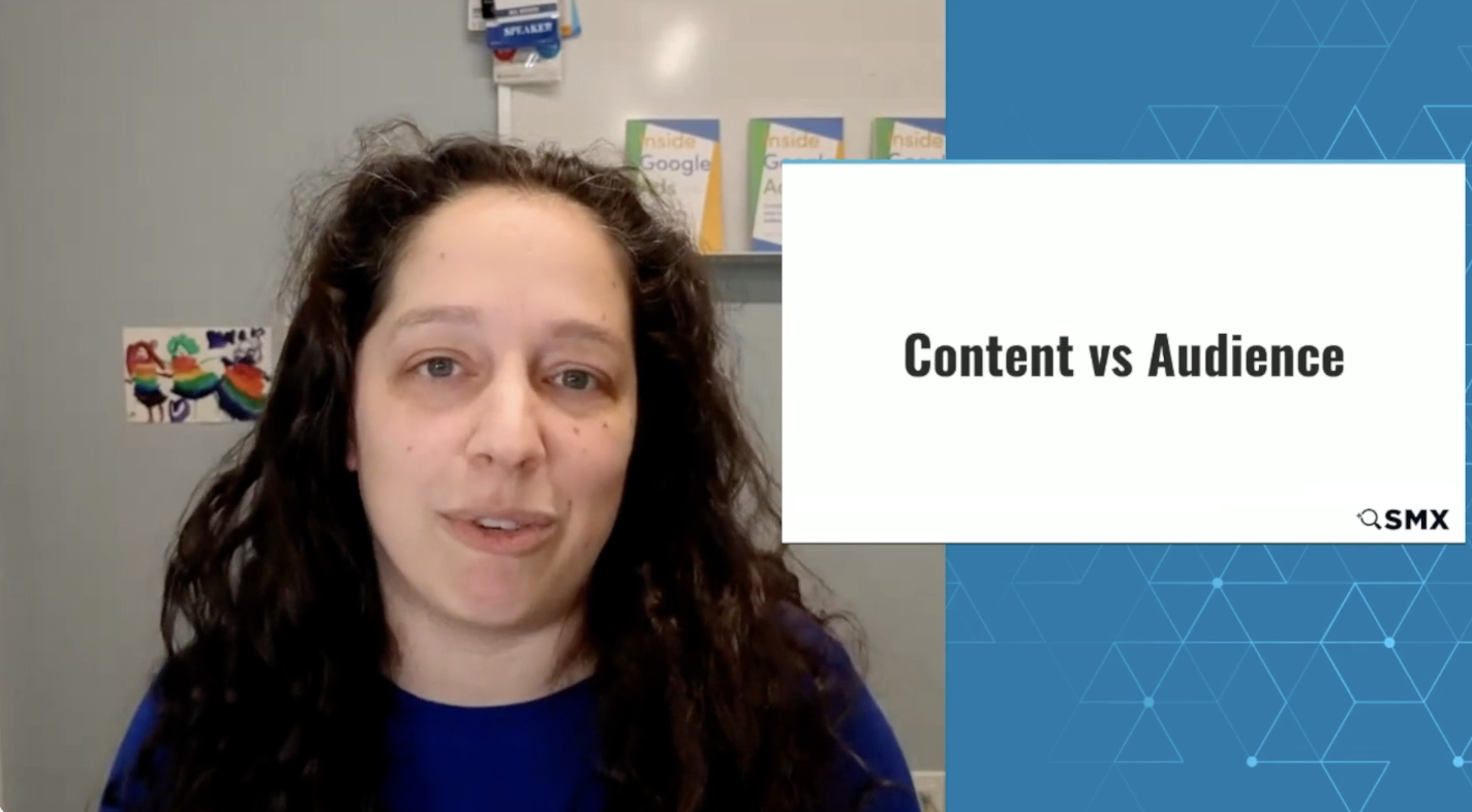 ```json
{
  "alt": "A person with long hair appears next to a presentation slide titled 'Content vs Audience' with books in the background.",
  "caption": "Exploring the balance between 'Content vs Audience,' this presentation delves into understanding viewer engagement with insightful discussions.",
  "description": "The image shows a person with long hair speaking during an online presentation. Next to them is a slide titled 'Content vs Audience.' The background features books and a colorful drawing, indicating a context of digital marketing or SEO. The SMX logo appears on the slide, suggesting a professional conference or workshop setting."
}
```