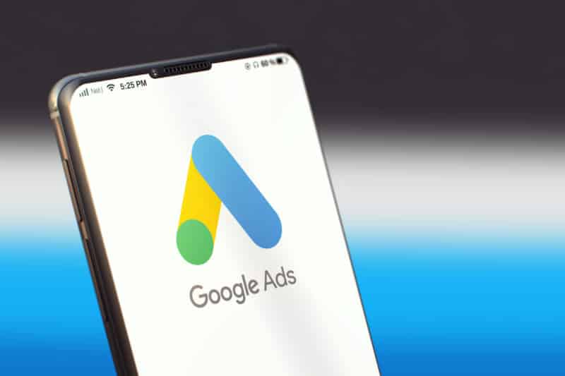 ```json
{
"alt": "Smartphone displaying Google Ads logo against a blurred background.",
"caption": "Discover the power of digital marketing with Google Ads, prominently displayed on a sleek smartphone.",
"description": "This image features a smartphone screen showing the Google Ads logo, characterized by its distinctive blue, yellow, and green icon. The device rests against a blurred, gradient background, emphasizing the logo's prominence. Ideal for illustrating topics related to digital marketing, online advertising, or Google's advertising platform."
}
```