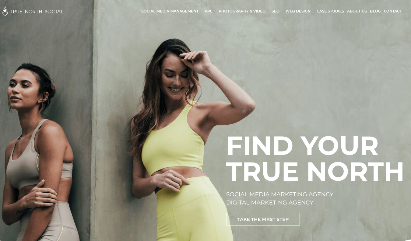 ```json
{
  "alt": "Two women in athletic wear pose against a textured wall with the text 'Find Your True North' displayed nearby.",
  "caption": "Embrace the journey of self-discovery and empowerment with True North Social. Discover how our digital marketing prowess can elevate your brand's presence.",
  "description": "This image features two women in stylish athletic wear standing against a textured wall. One woman is smiling while adjusting her hair, depicting a sense of confidence and ease. The text 'Find Your True North' is prominently displayed alongside, emphasizing a theme of discovery and direction. Keywords: athletic, women, empowerment, marketing, brand, social media."
}
```
